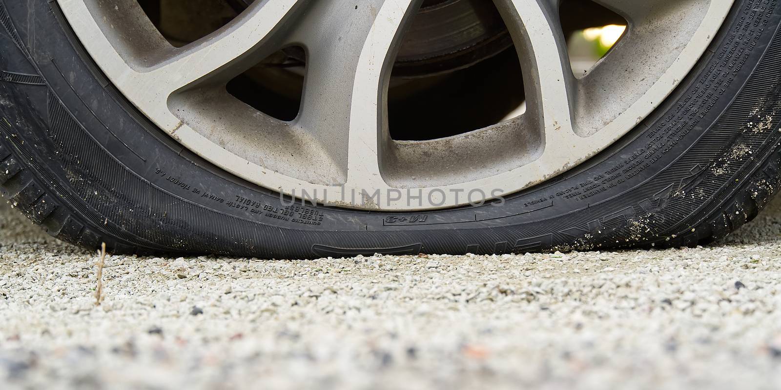 Close-up of Flat rear tire on car. Damaged rear wheels on parking place. The right rear broken weel.