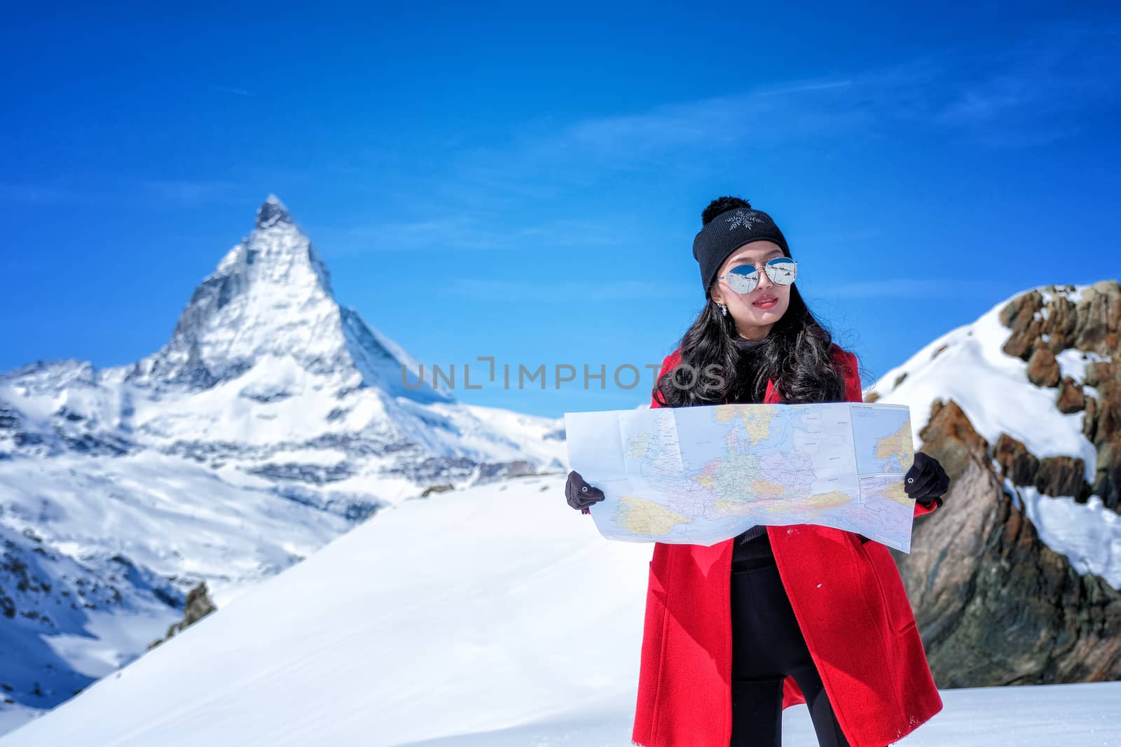 Young female tourist looking map at Matterhorn in Switzerland with a magnificent panoramic view of the Swiss Skyline.