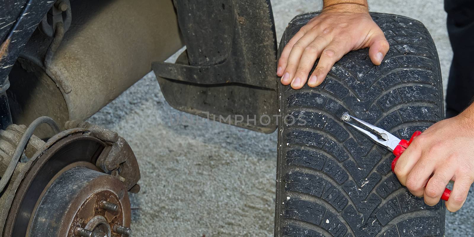 screw in car flat tire. mechanic repair a tire puncture from a nail or screw. car repair and maintenance concept by PhotoTime