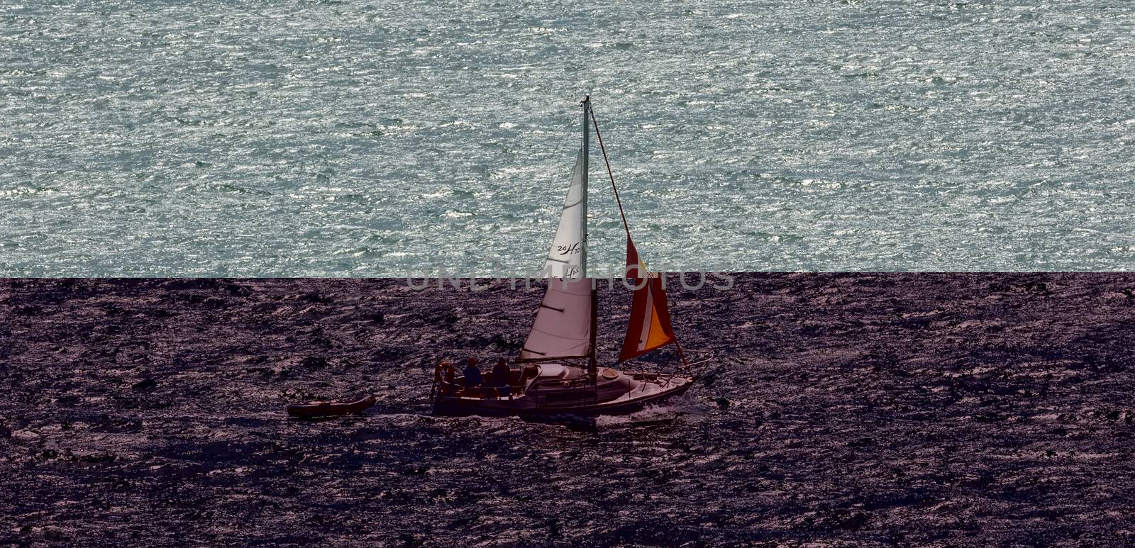 Portland Harbor, UK - July 2, 2020: White sailboat sailing in the harbor. Small rescue boat tagging along.