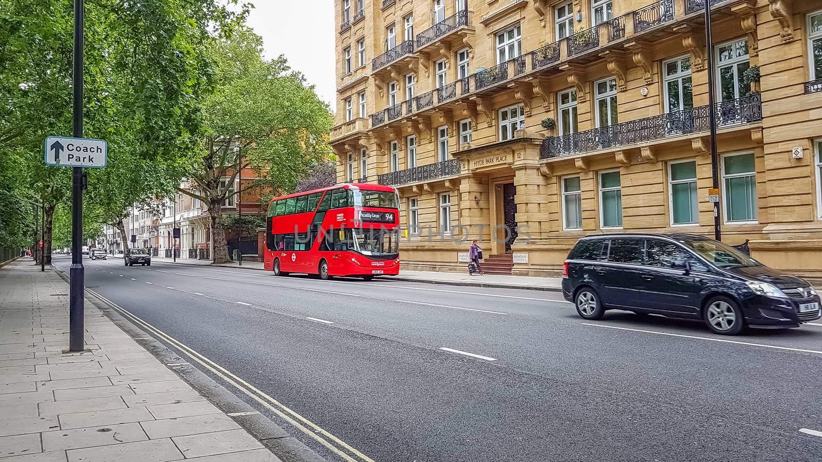 London, UK - July 8, 2020: Modern red double-decker bus passing by Hyde Park Place building in central London. It says on it - Piccadilly Circus 94.