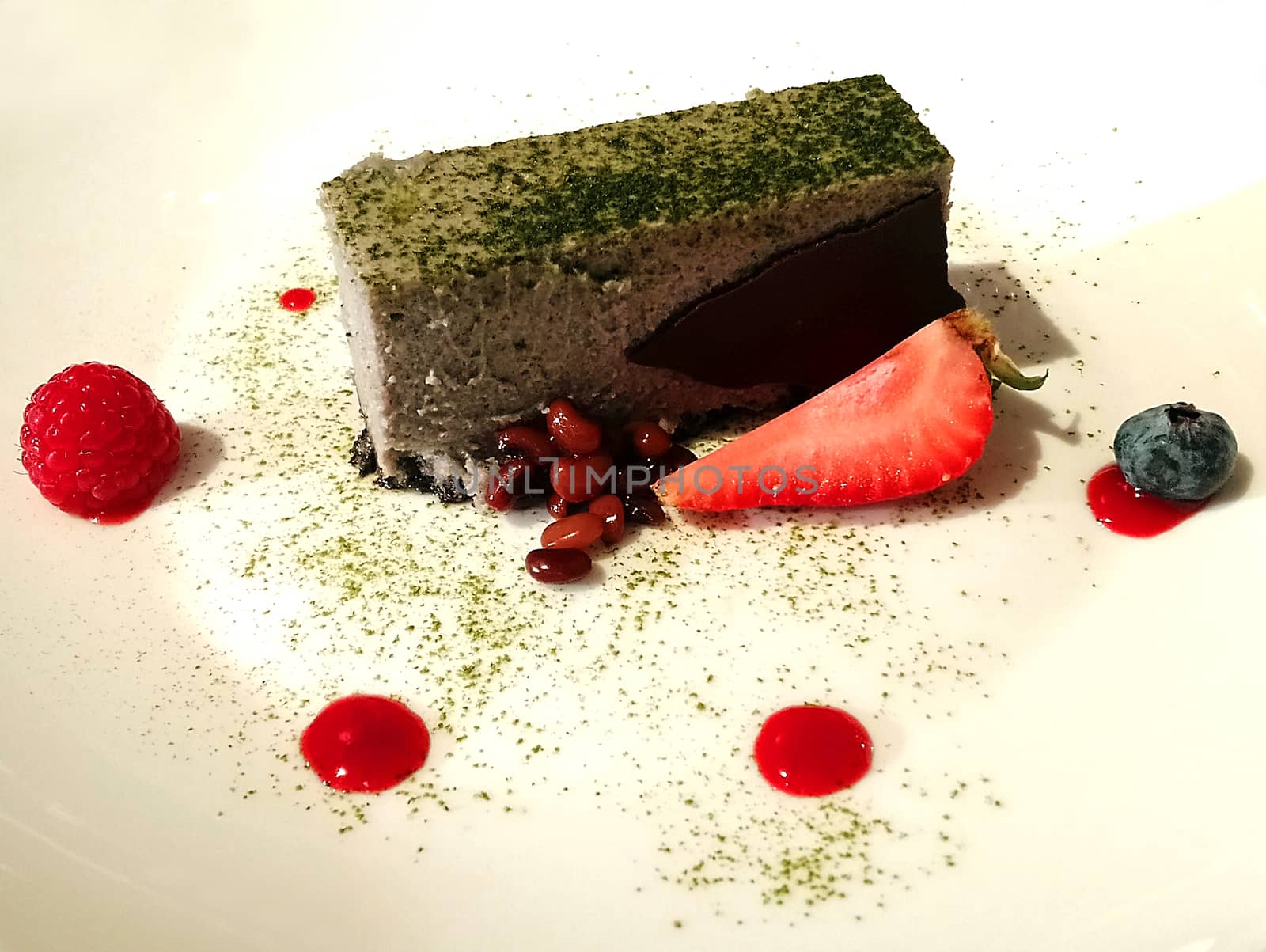 Chocolate cake with matcha powder and berries on white plate serve in hotel restaurant