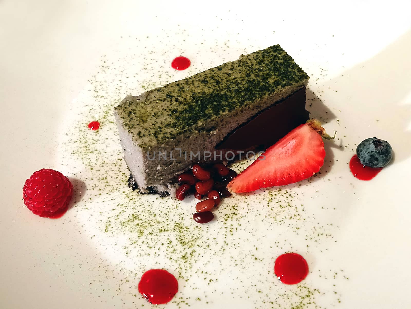 Chocolate cake with matcha powder and berries on white plate serve in hotel restaurant