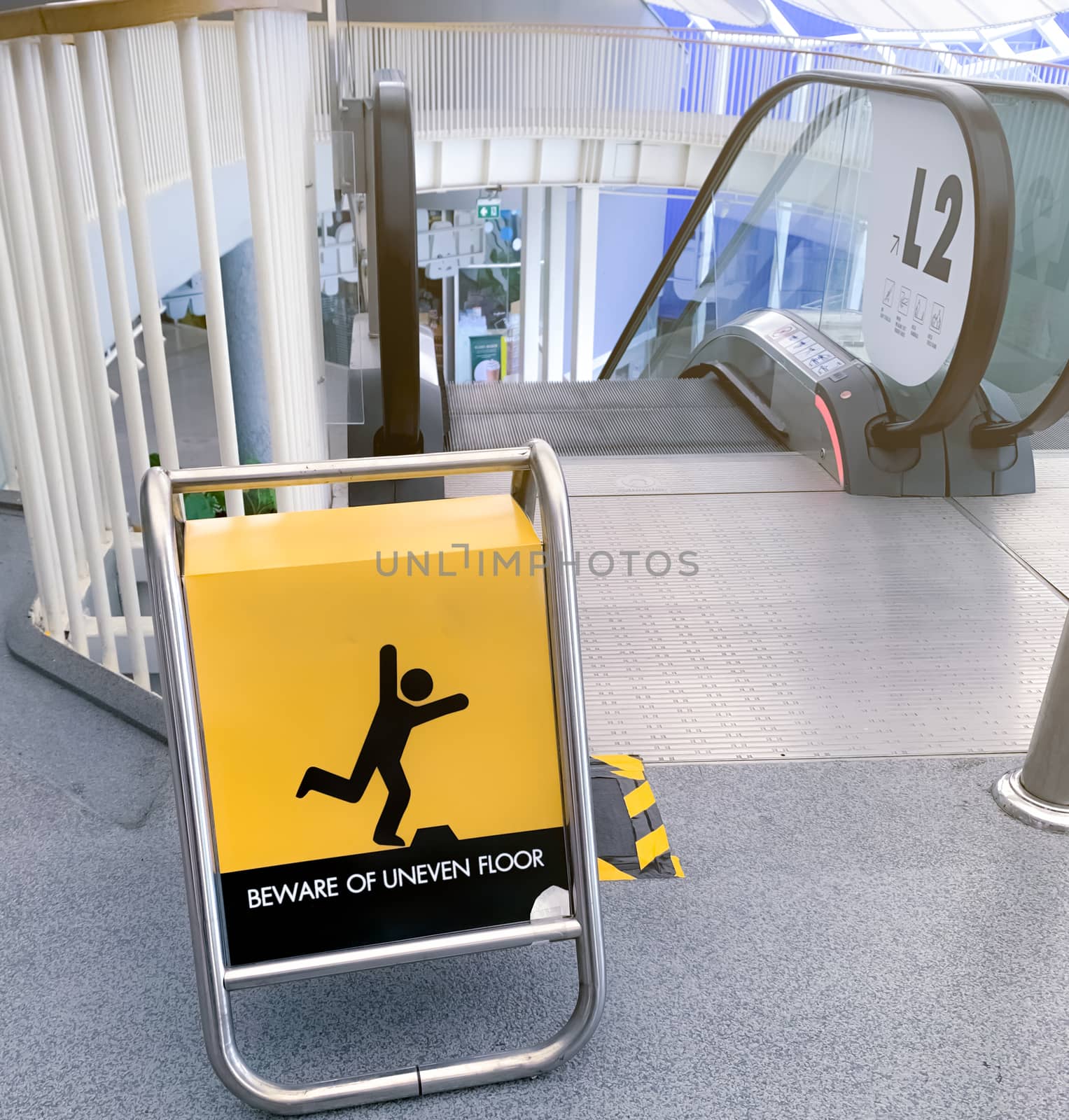 Beware uneven floor warning sign on yellow board in front of esc by Fahroni