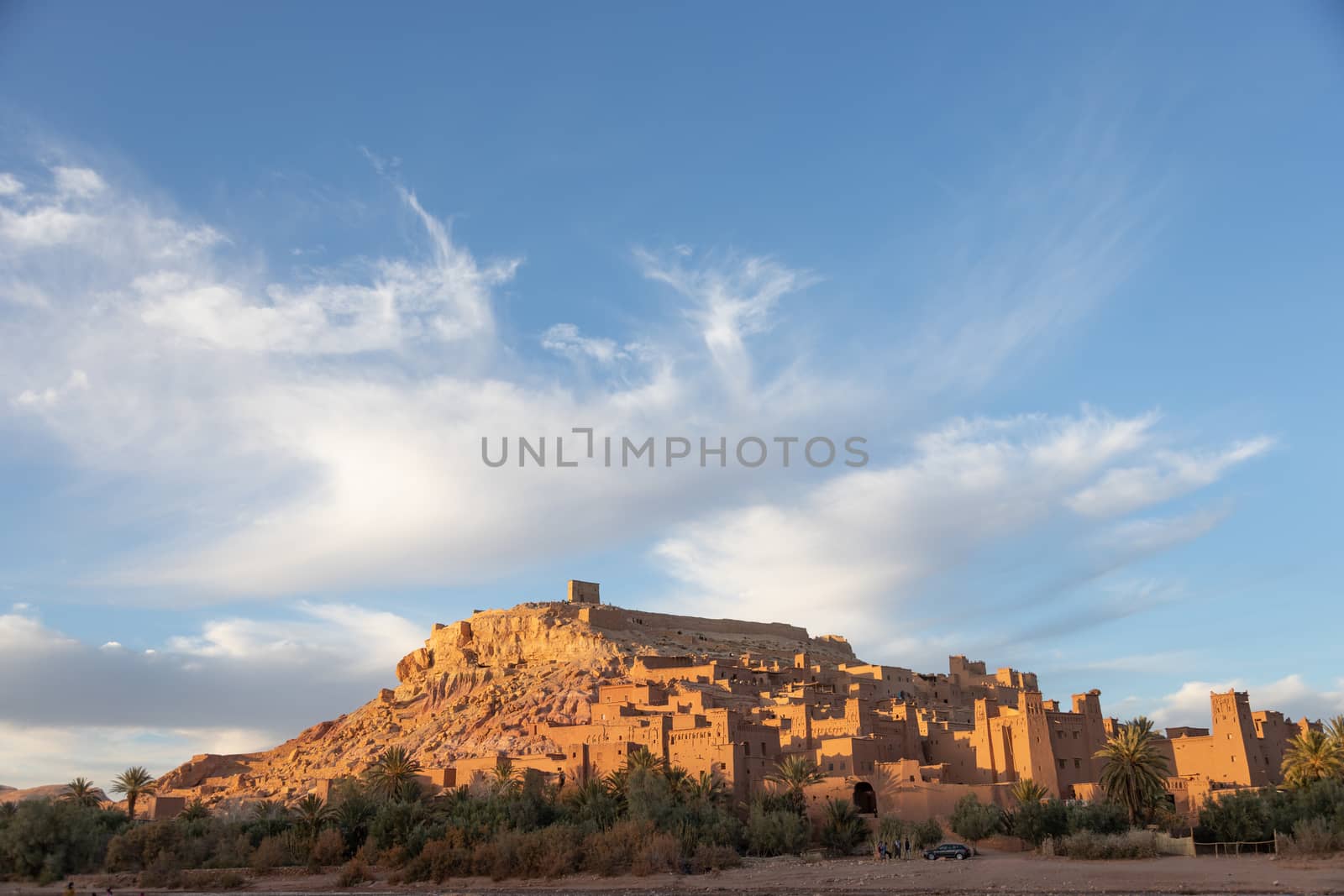 Ait Ben Haddou ksar Morocco, ancient fortress that is a Unesco Heritage site. Beautiful late afternoon light with honey, gold coloured mud brick construction against a blue sly with clouds the kasbah, or fortified town dates from 11th cent. and is on the former caravan route from the Sahara and Marrakech. The location has been used for many famous movies. High quality photo