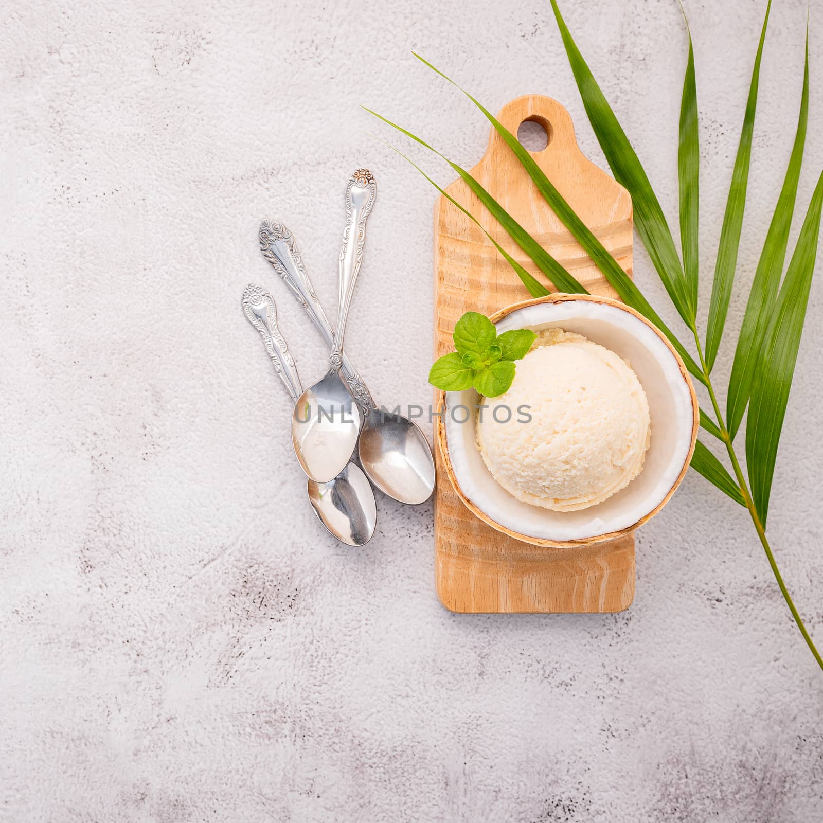 Coconut ice cream flavours in half of coconut setup on white stone background. Summer and Sweet menu concept.