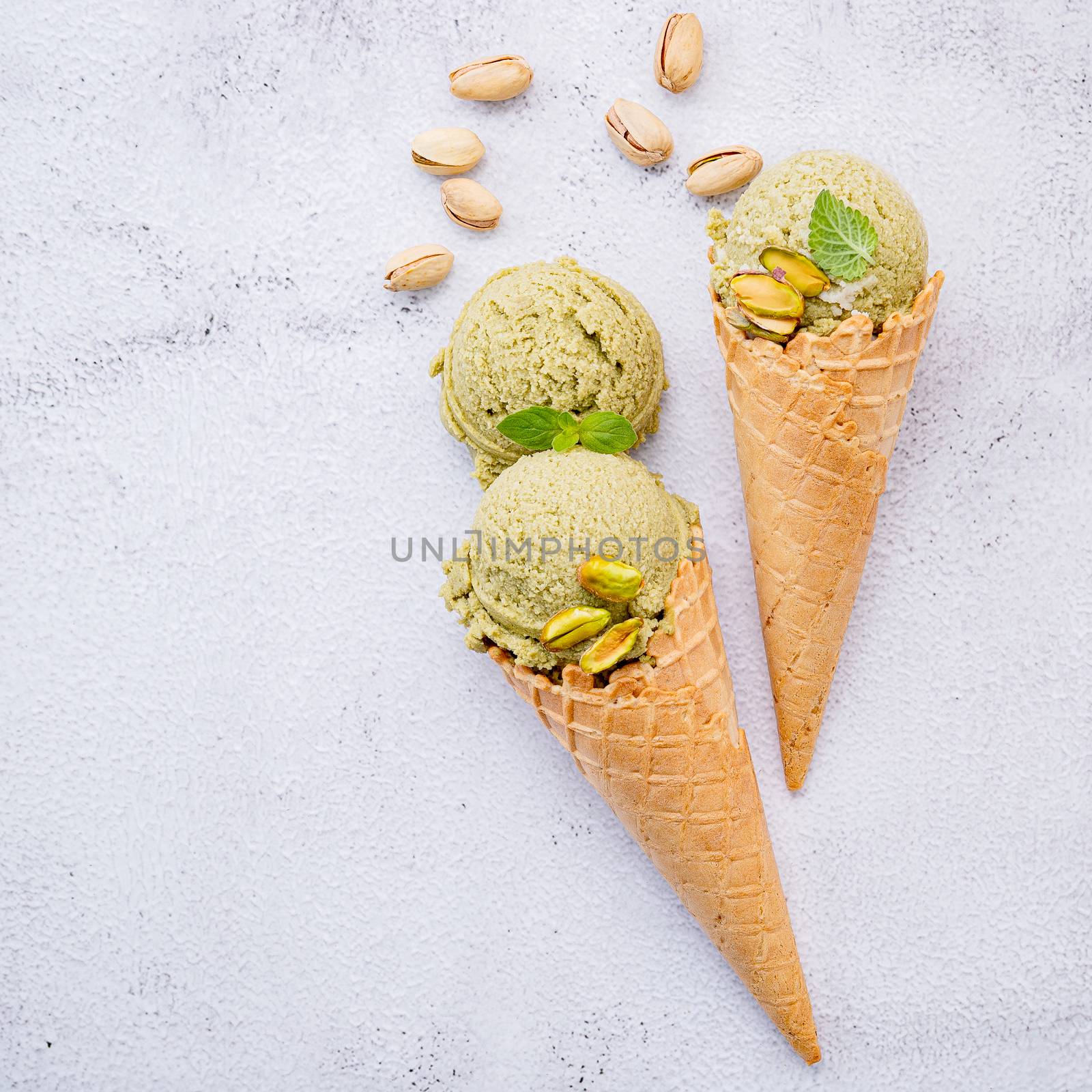 Pistachio ice cream in cones  with pistachio nuts setup on white by kerdkanno