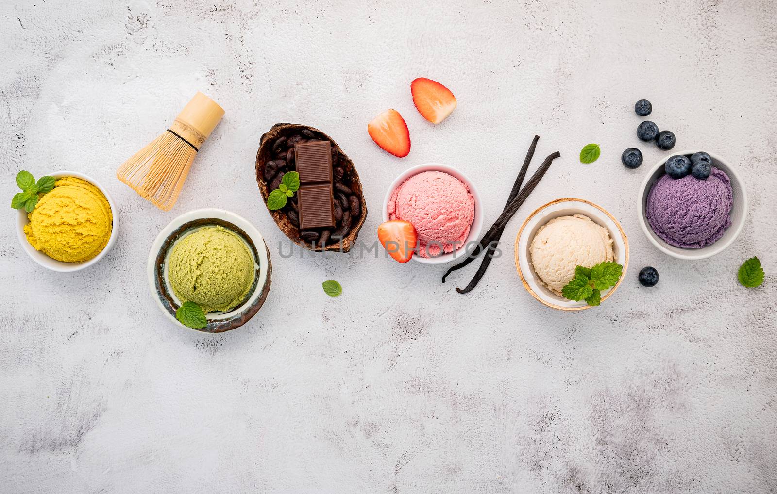 Various of ice cream  flavours in bowl blueberry ,green tea ,coconut ,strawberry and chocolate  setup on white stone background .