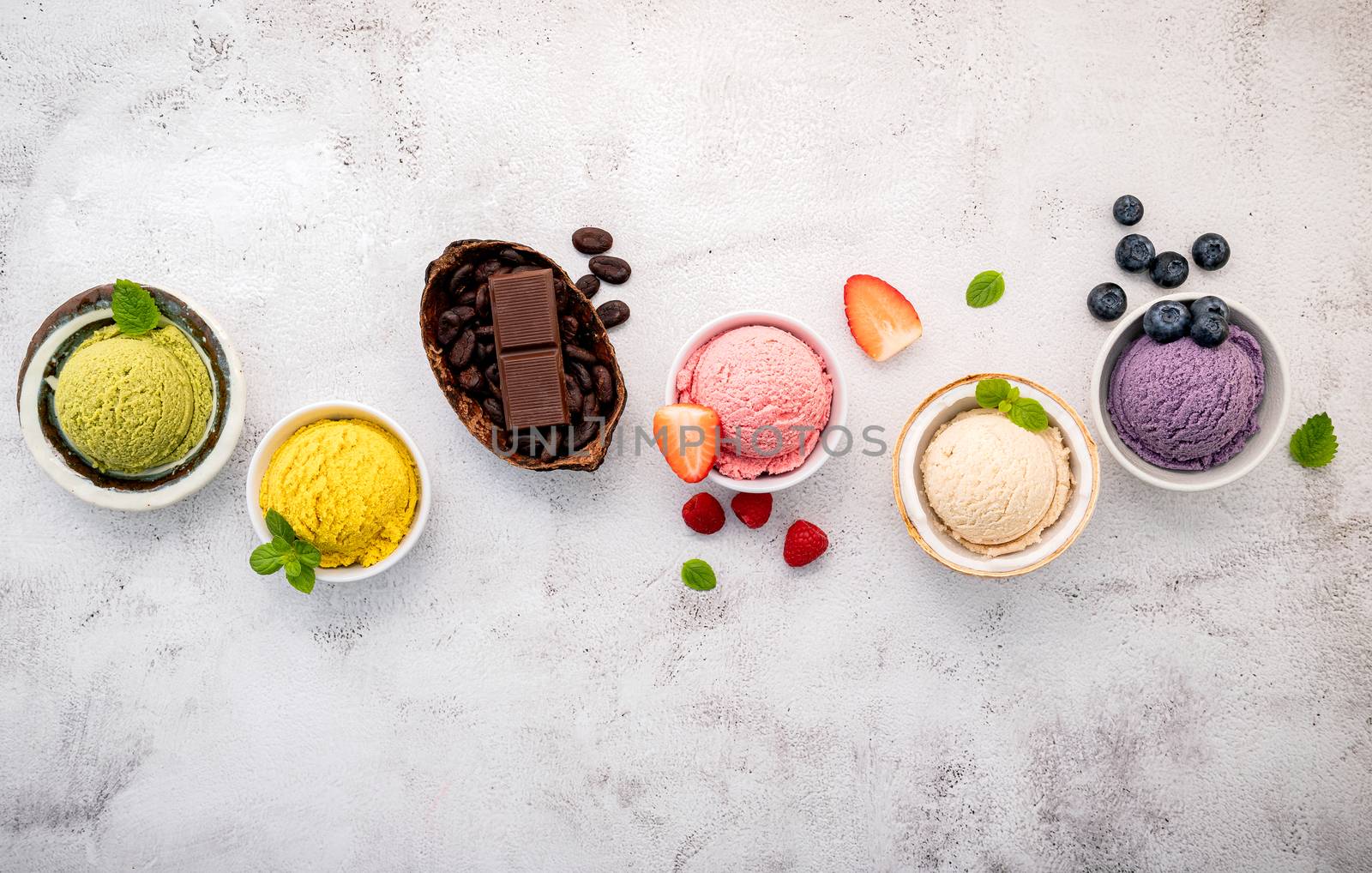 Various of ice cream  flavours in bowl blueberry ,green tea ,coconut ,strawberry and chocolate  setup on white stone background .