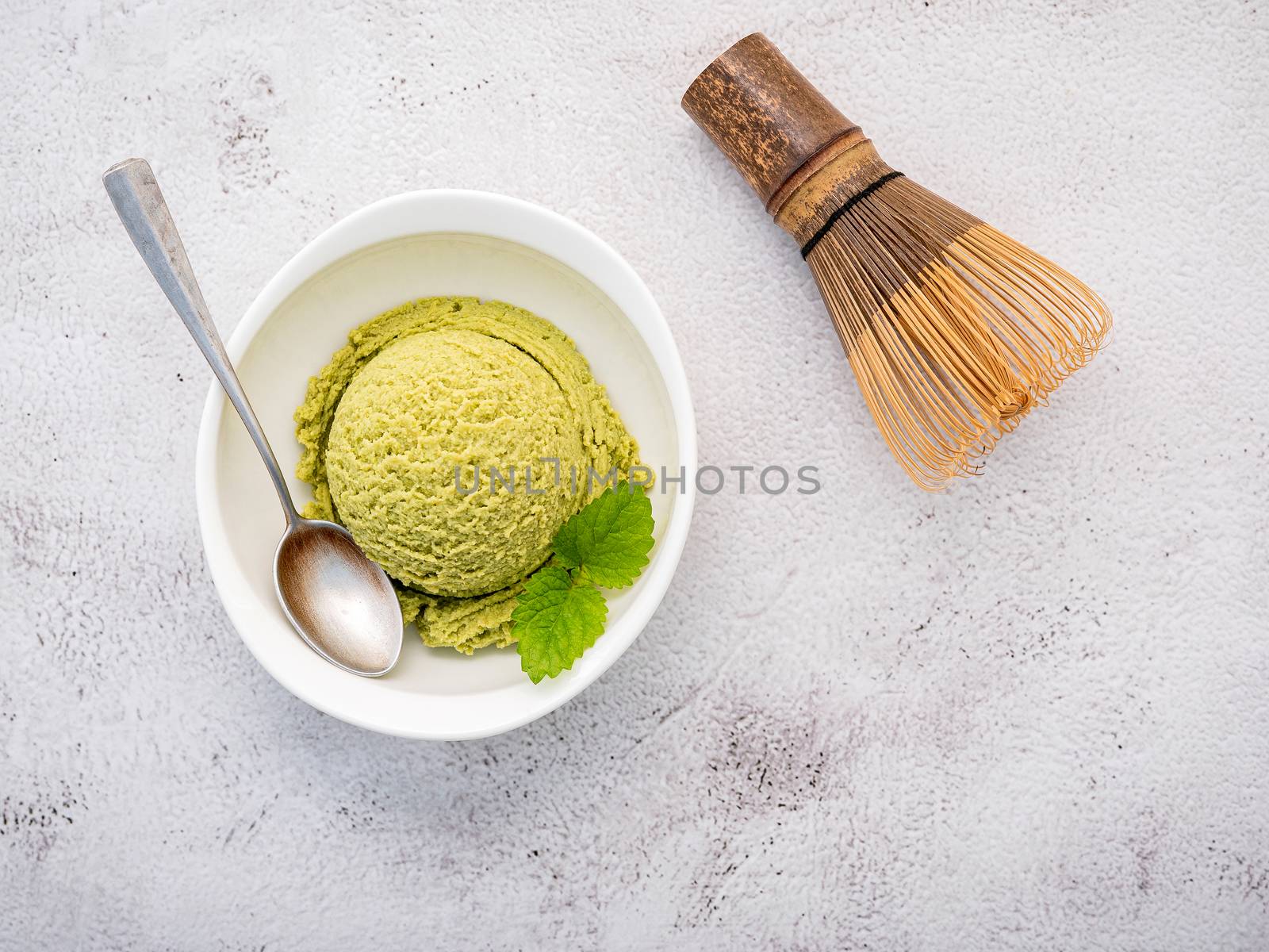 Matcha green tea ice cream with matcha whisk brush  setup on white stone background . Summer and Sweet menu concept.