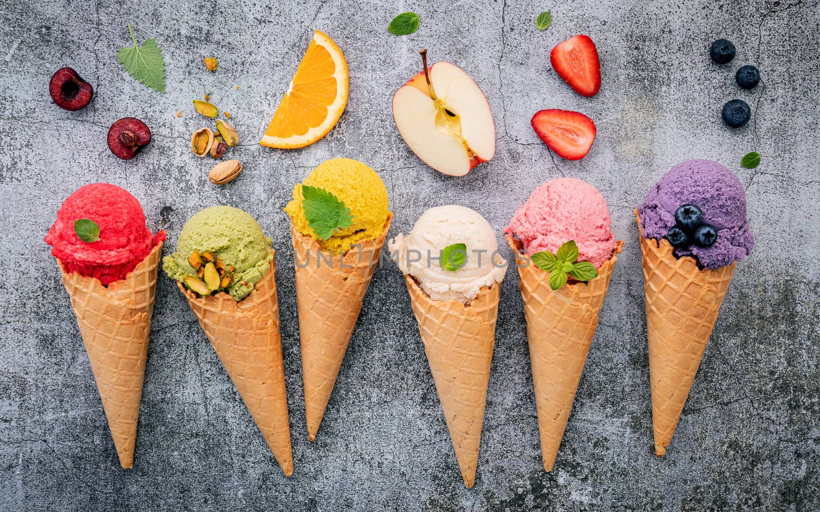 Various of ice cream flavor in cones blueberry ,green tea ,pistachio ,almond ,orange and cherry setup on dark stone background . Summer and Sweet menu concept.