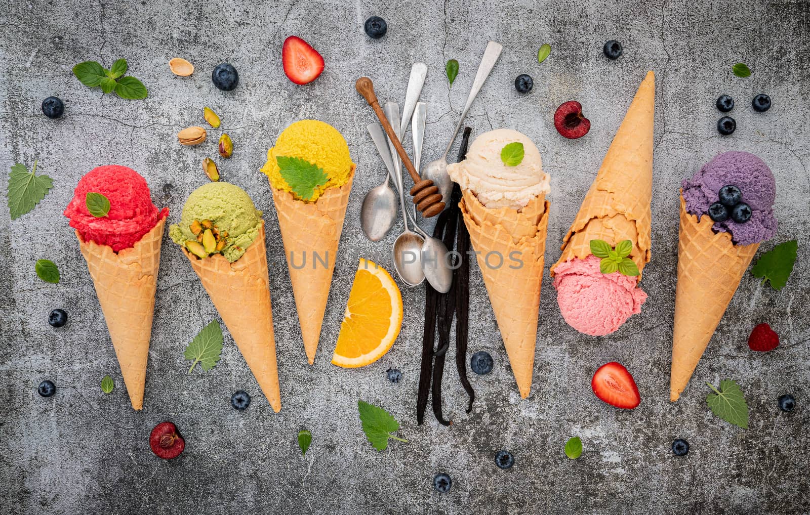 Various of ice cream flavor in cones blueberry ,green tea ,pistachio ,almond ,orange and cherry setup on dark stone background . Summer and Sweet menu concept.