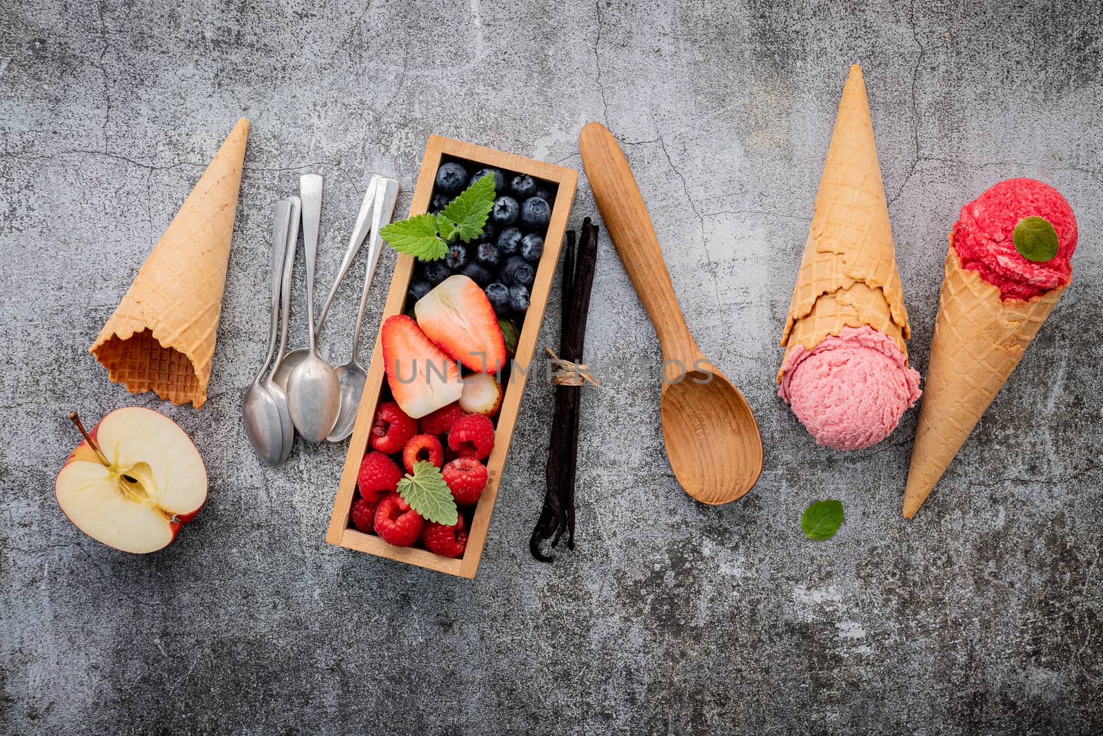 Various of ice cream flavor in cones with berries in wooden box setup on concrete background . Summer and Sweet menu concept.