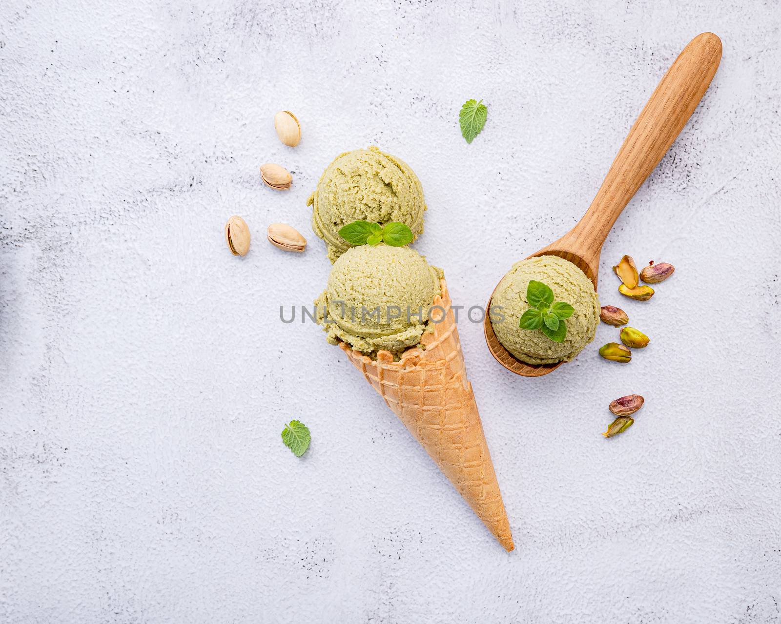 Pistachio ice cream in cones  with pistachio nuts setup on white stone background . Summer and Sweet menu concept.