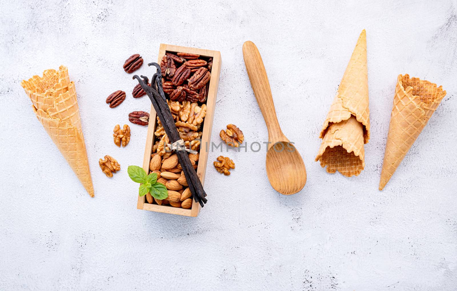 Empty  ice cream cones  with mixed nut setup on white stone background . Summer and Sweet menu concept.