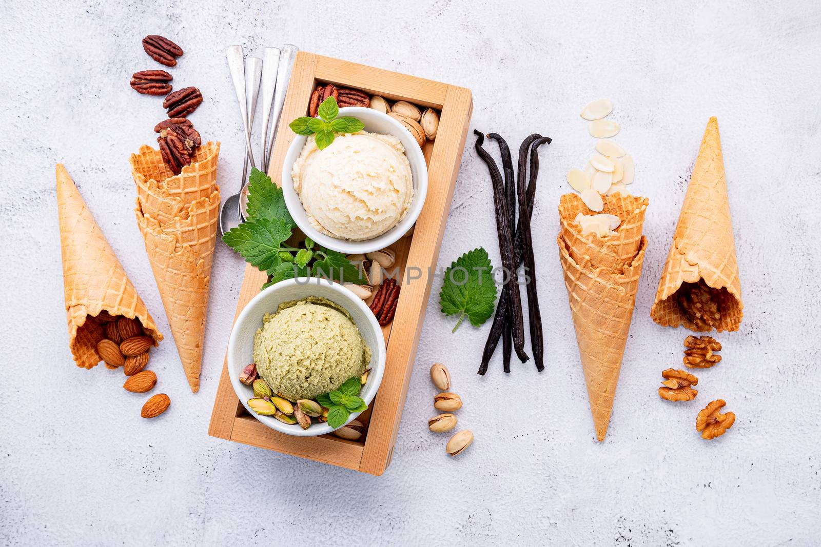 Pistachio and vanila ice cream in bowl  with mixed nuts setup on white stone background . Summer and Sweet menu concept.