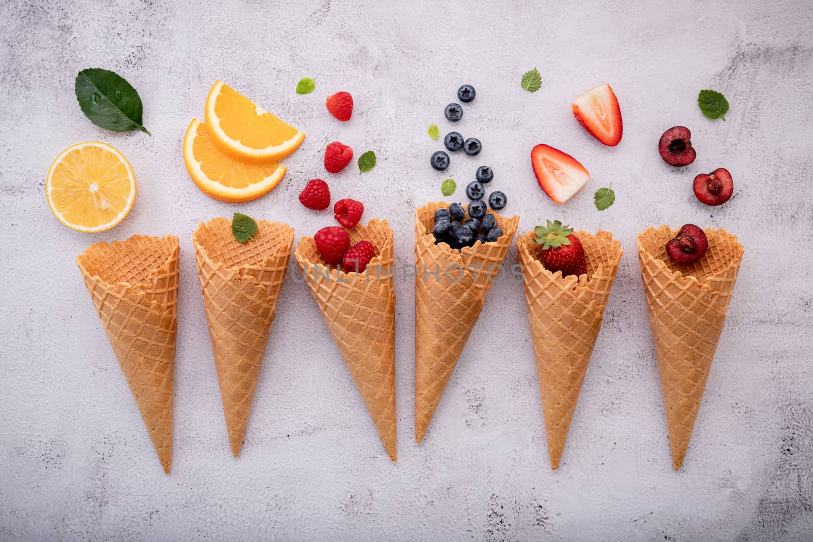 Various of fruits  in cones blueberry ,strawberry ,raspberries and strawberry setup on white stone background . Summer and Sweet menu concept.