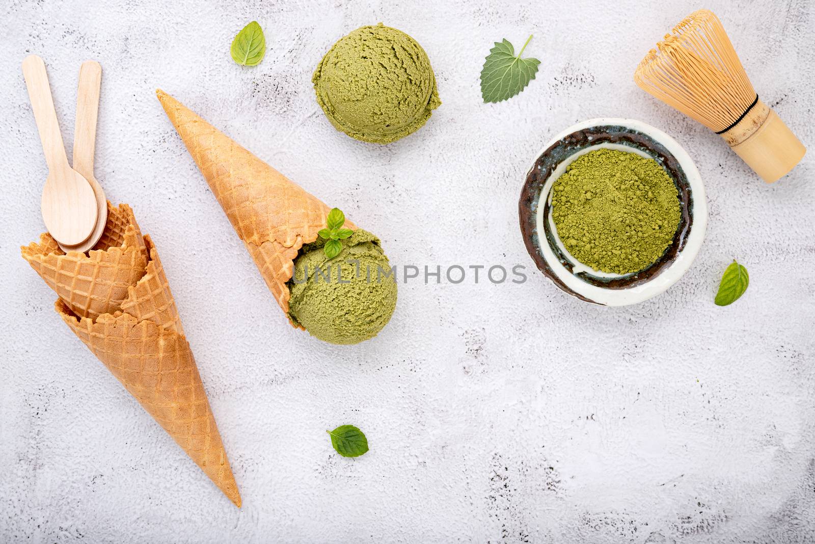 Matcha green tea ice cream with waffle cone and mint leaves  setup on white stone background . Summer and Sweet menu concept.