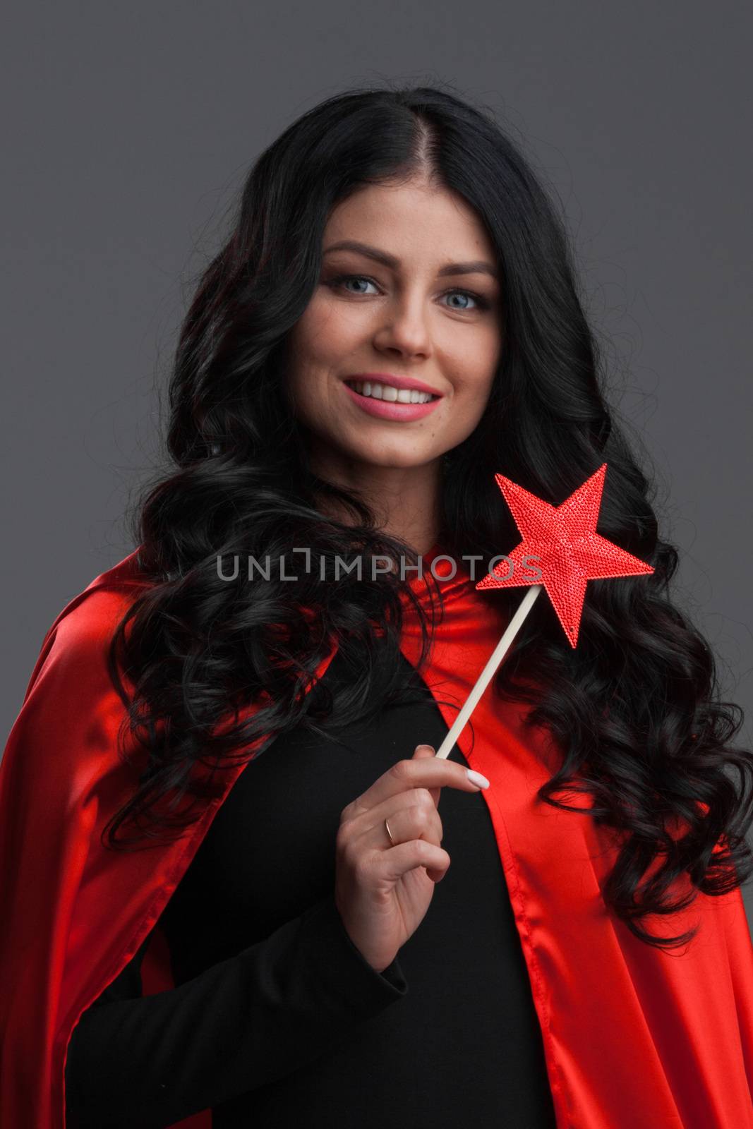 Woman with star shaped magic wand on gray background, halloween costume