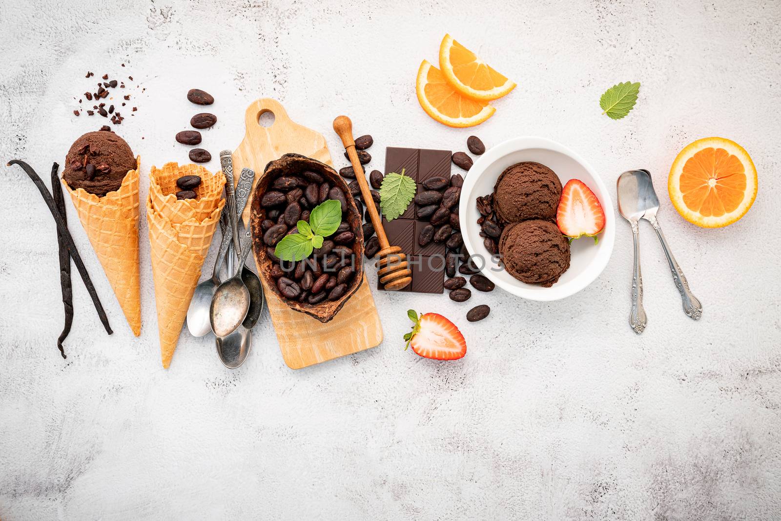 Chocolate ice cream flavours in bowl with dark chocolate and cacao nibs setup on white stone background .