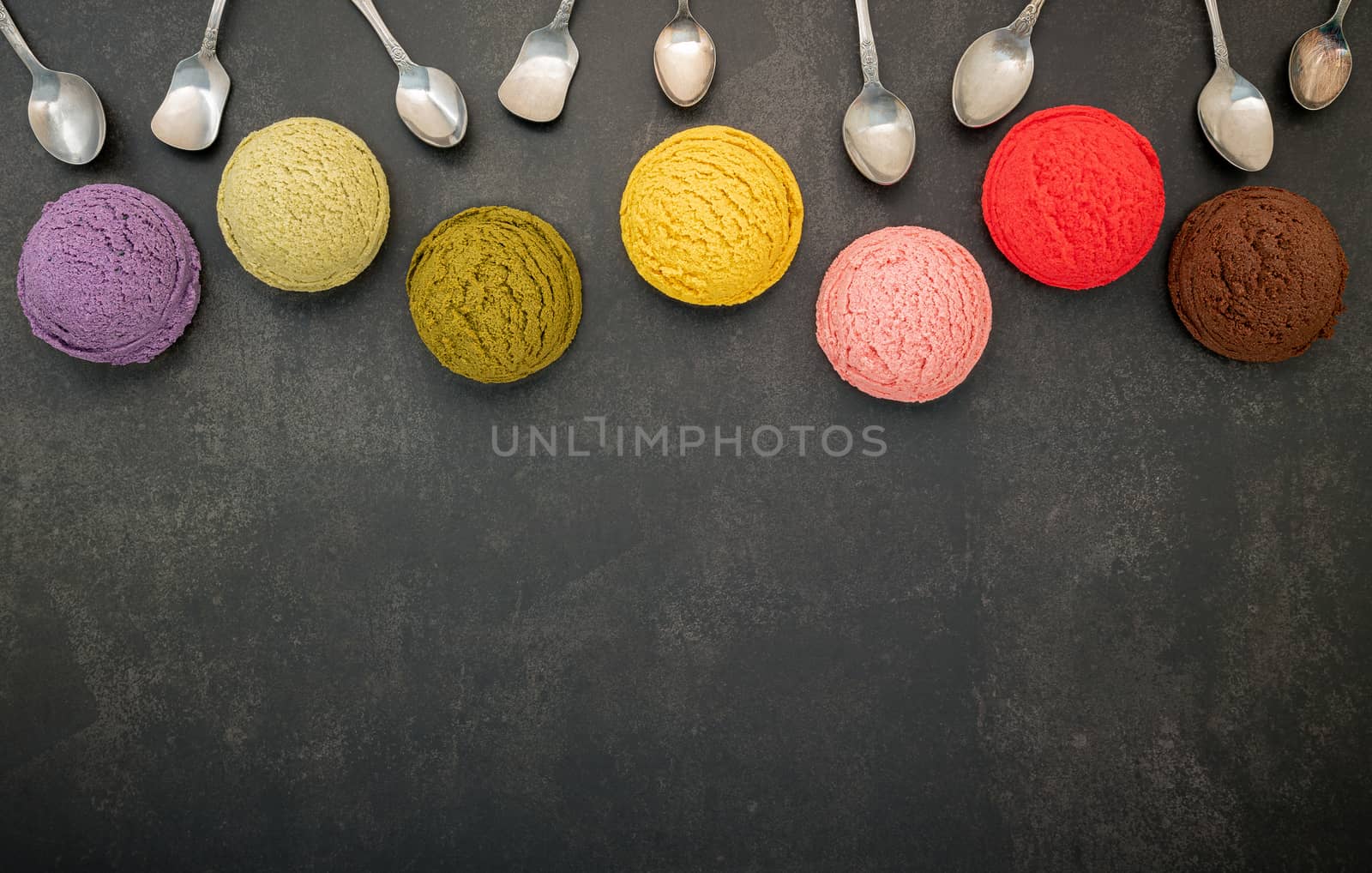 Various of ice cream flavor blueberry ,pistachio ,almond , orange, green tea and chocolate setup on dark stone background . Summer and Sweet menu concept.