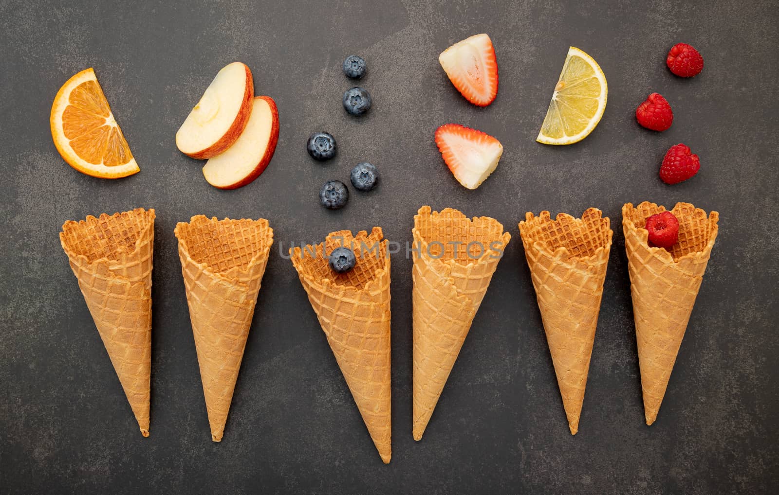 Various of fruits  in cones blueberry ,strawberry ,raspberries and orange setup on white stone background.  Summer and Sweet menu concept.