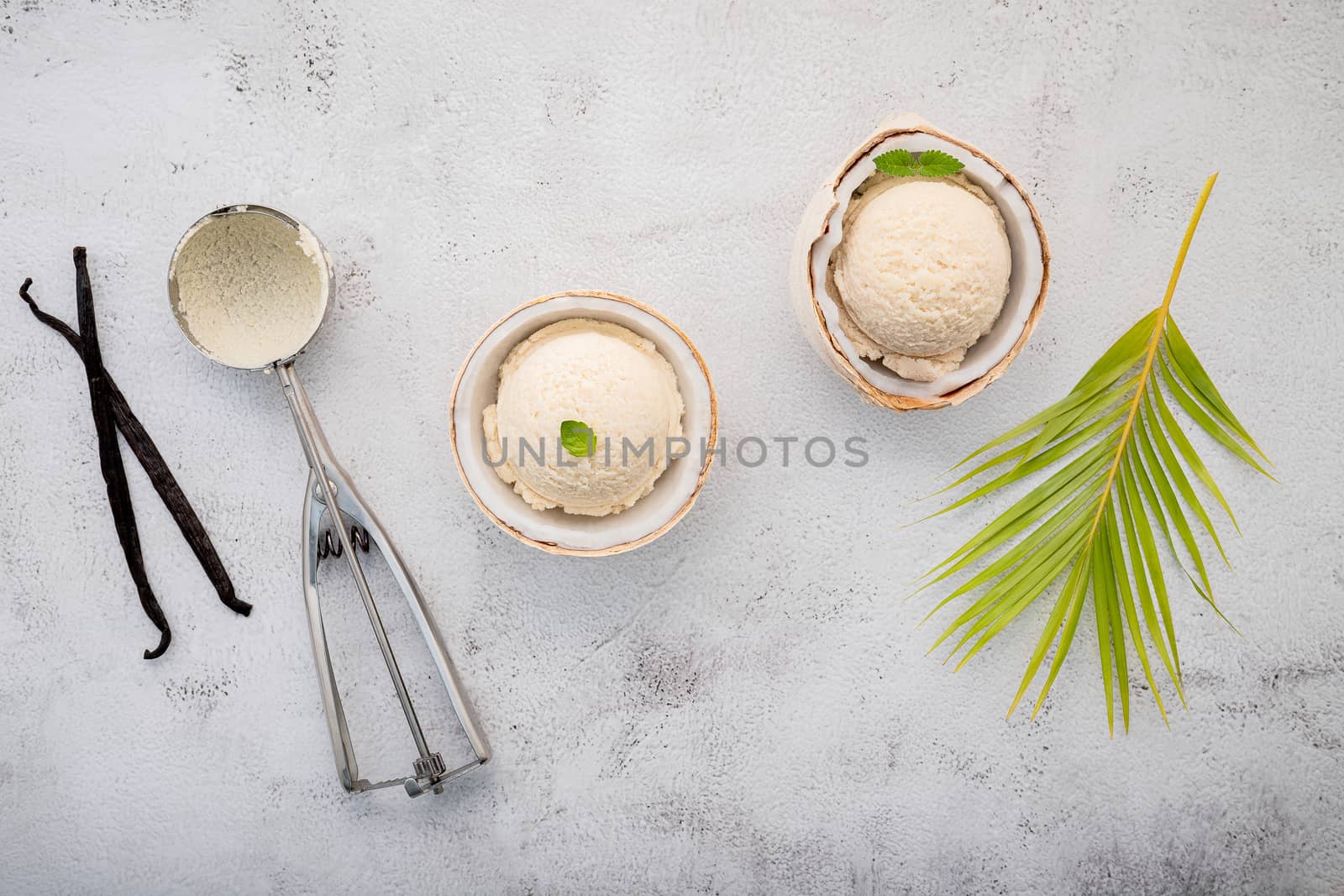 Coconut ice cream flavours in half of coconut setup on white stone background. Summer and Sweet menu concept.