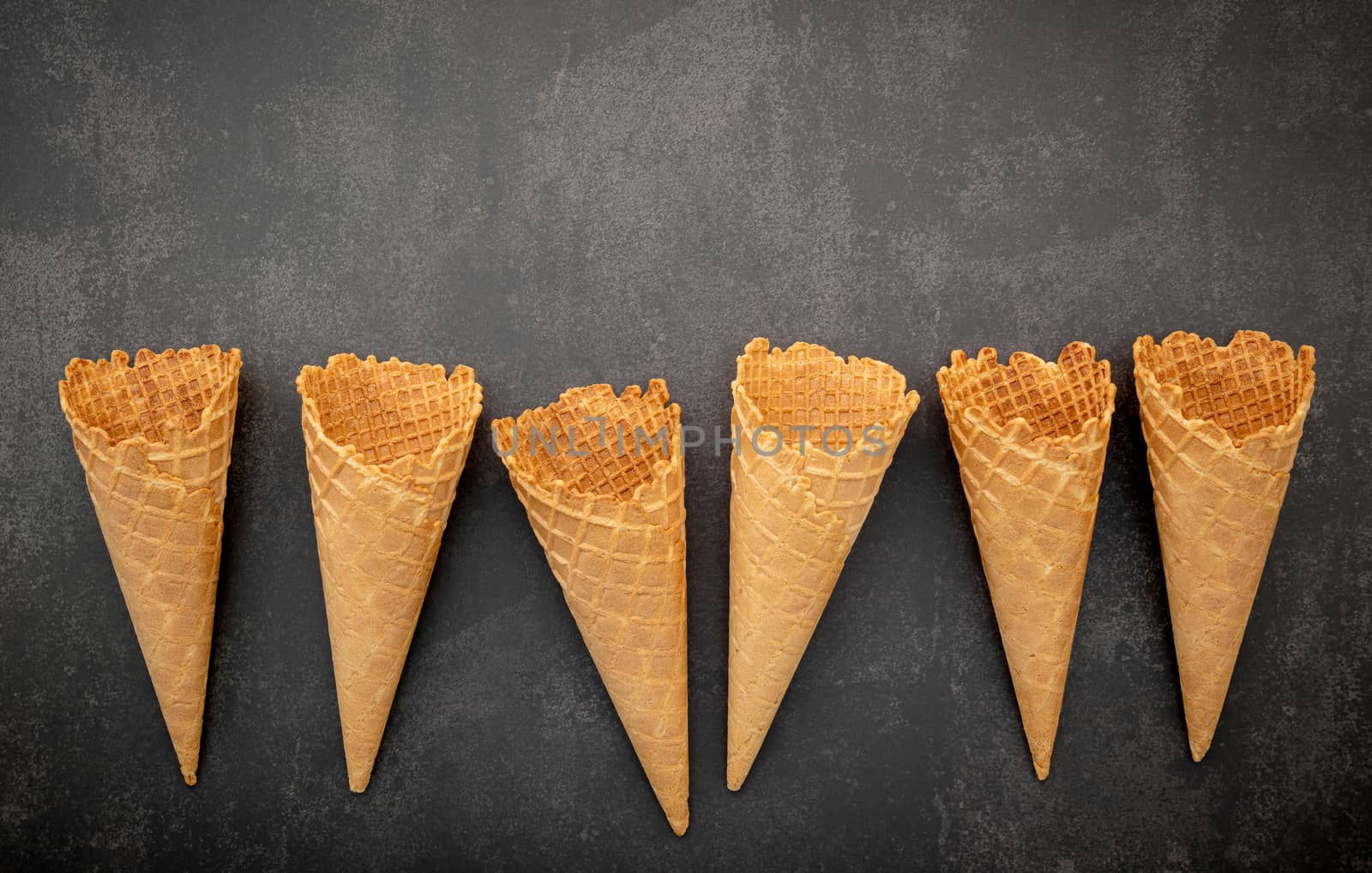 Flat lay ice cream cones collection on dark stone background . Blank crispy ice cream cone with copy space for sweets menu design.