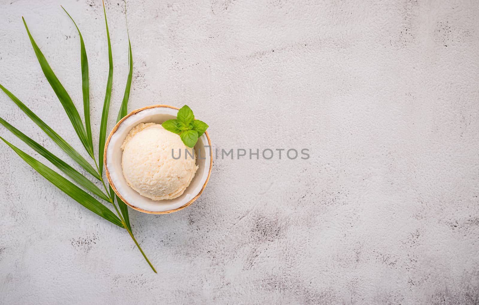 Coconut ice cream flavours in half of coconut setup on white stone background. Summer and Sweet menu concept.