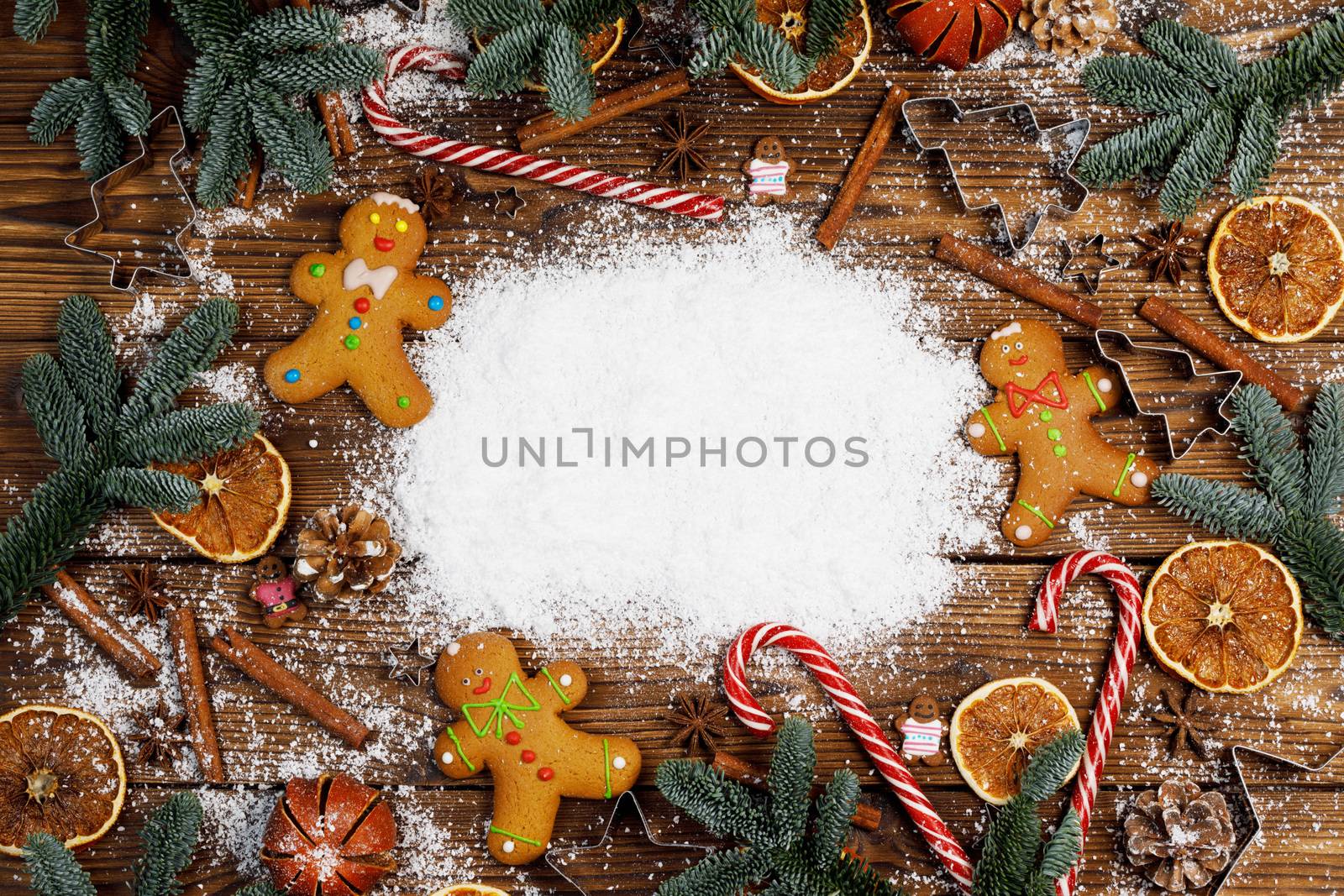 Christmas food frame. Gingerbread cookies, spices and decorations on wooden background with white copy space on snow