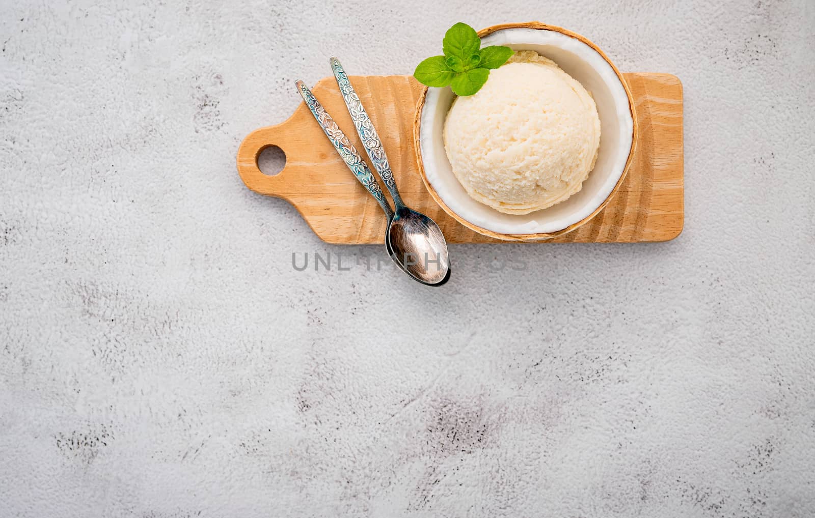 Coconut ice cream flavours in half of coconut setup on white stone background. Summer and Sweet menu concept.