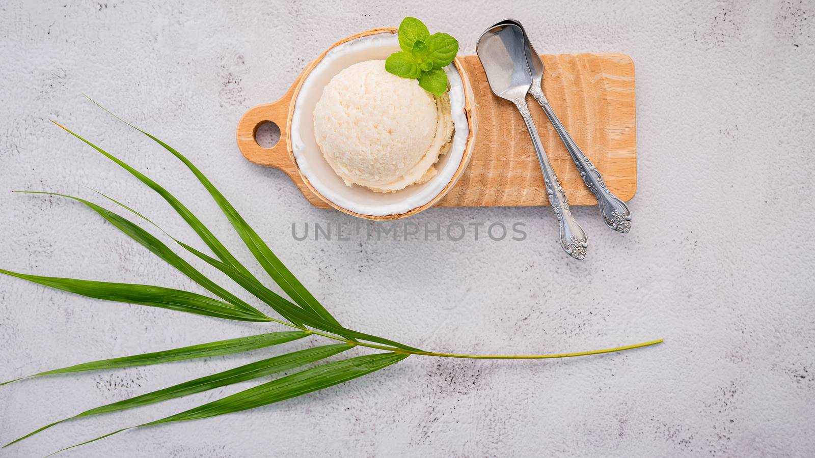 Coconut ice cream flavours in half of coconut setup on white stone background. Summer and Sweet menu concept.