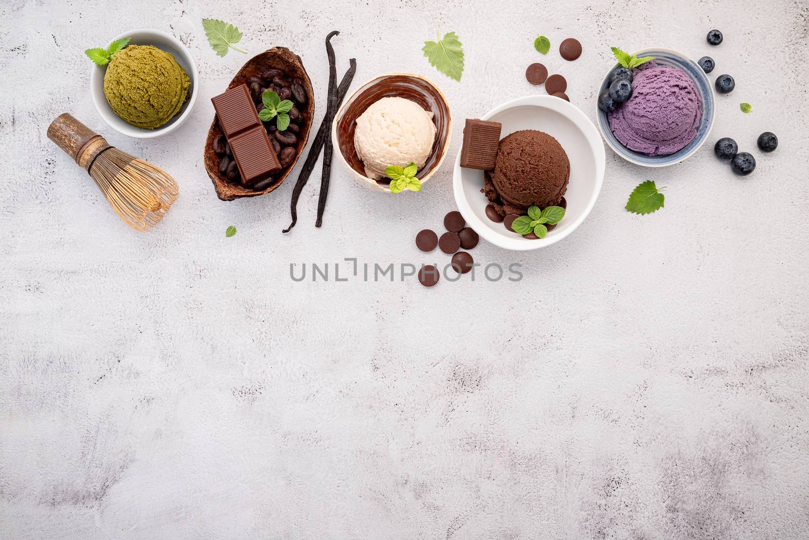 Various of ice cream  flavours in bowl blueberry ,green tea ,coconut  and chocolate  setup on white stone background .