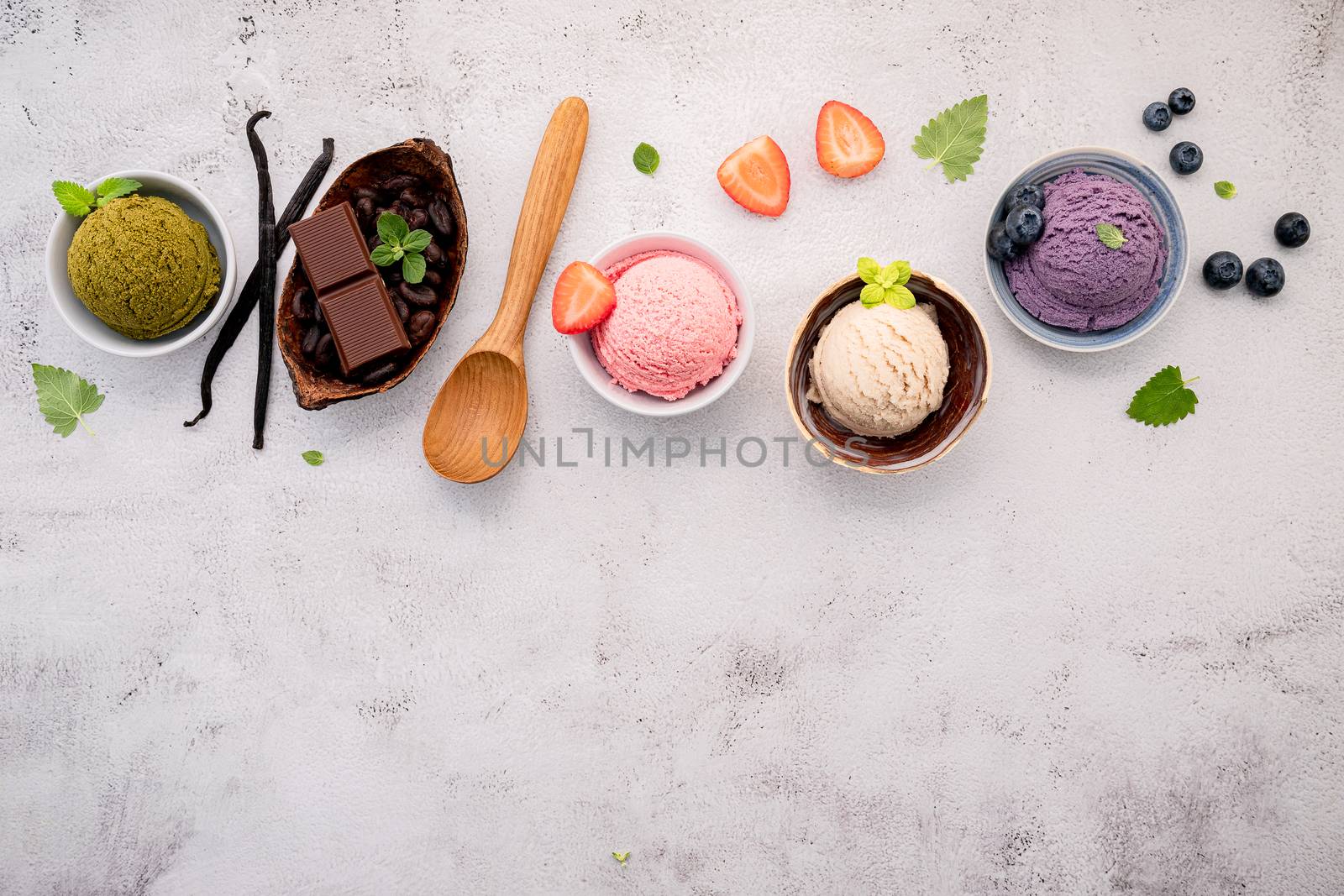 Various of ice cream  flavours in bowl blueberry ,green tea ,coconut ,strawberry and chocolate  setup on white stone background .