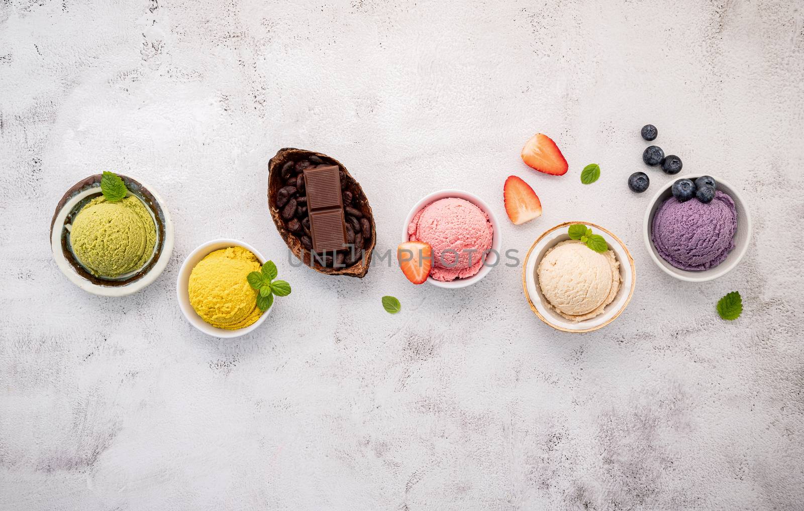 Various of ice cream  flavours in bowl blueberry ,green tea ,coconut ,strawberry and chocolate  setup on white stone background .