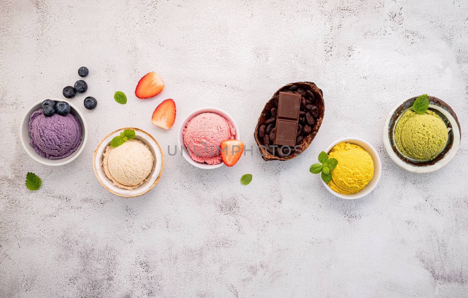 Various of ice cream  flavours in bowl blueberry ,green tea ,coconut ,strawberry and chocolate  setup on white stone background .