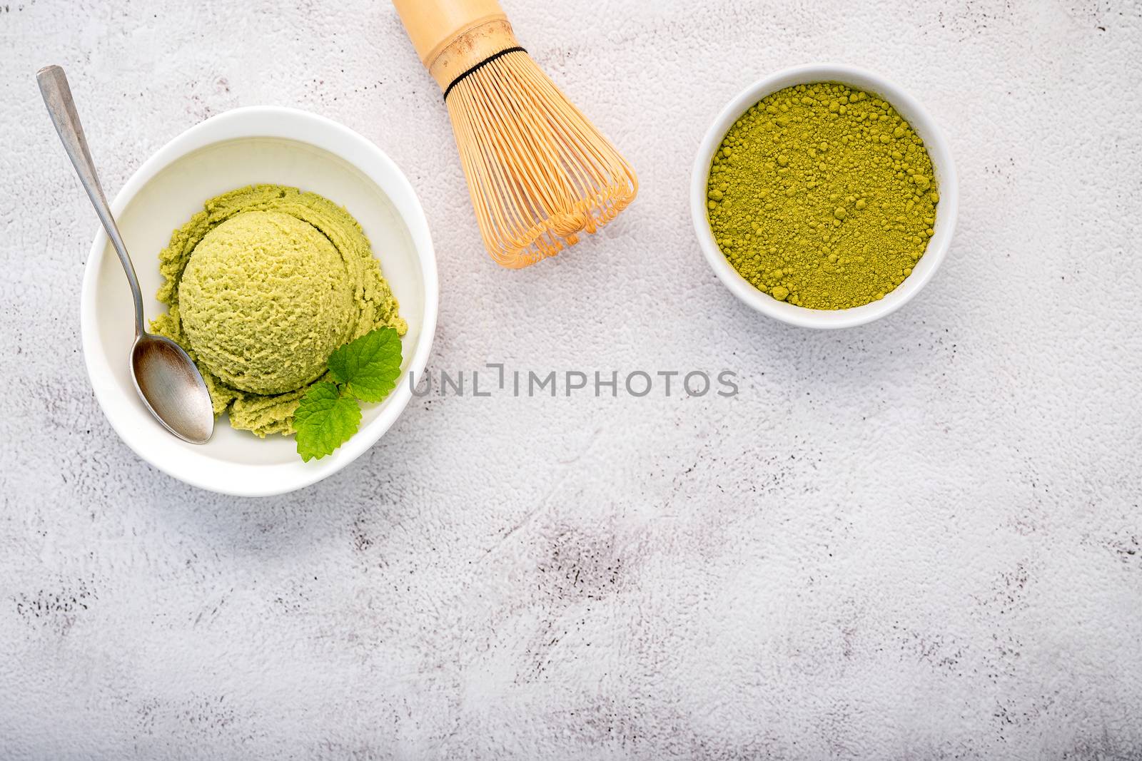 Matcha green tea ice cream with matcha whisk brush  setup on white stone background . Summer and Sweet menu concept.