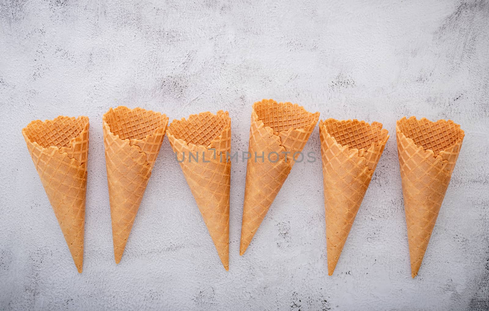 Flat lay ice cream cones collection on white concrete background . Blank crispy ice cream cone with copy space for sweets menu design.