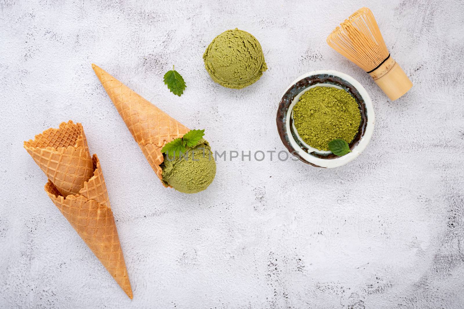 Matcha green tea ice cream with waffle cone and mint leaves  setup on white stone background . Summer and Sweet menu concept.