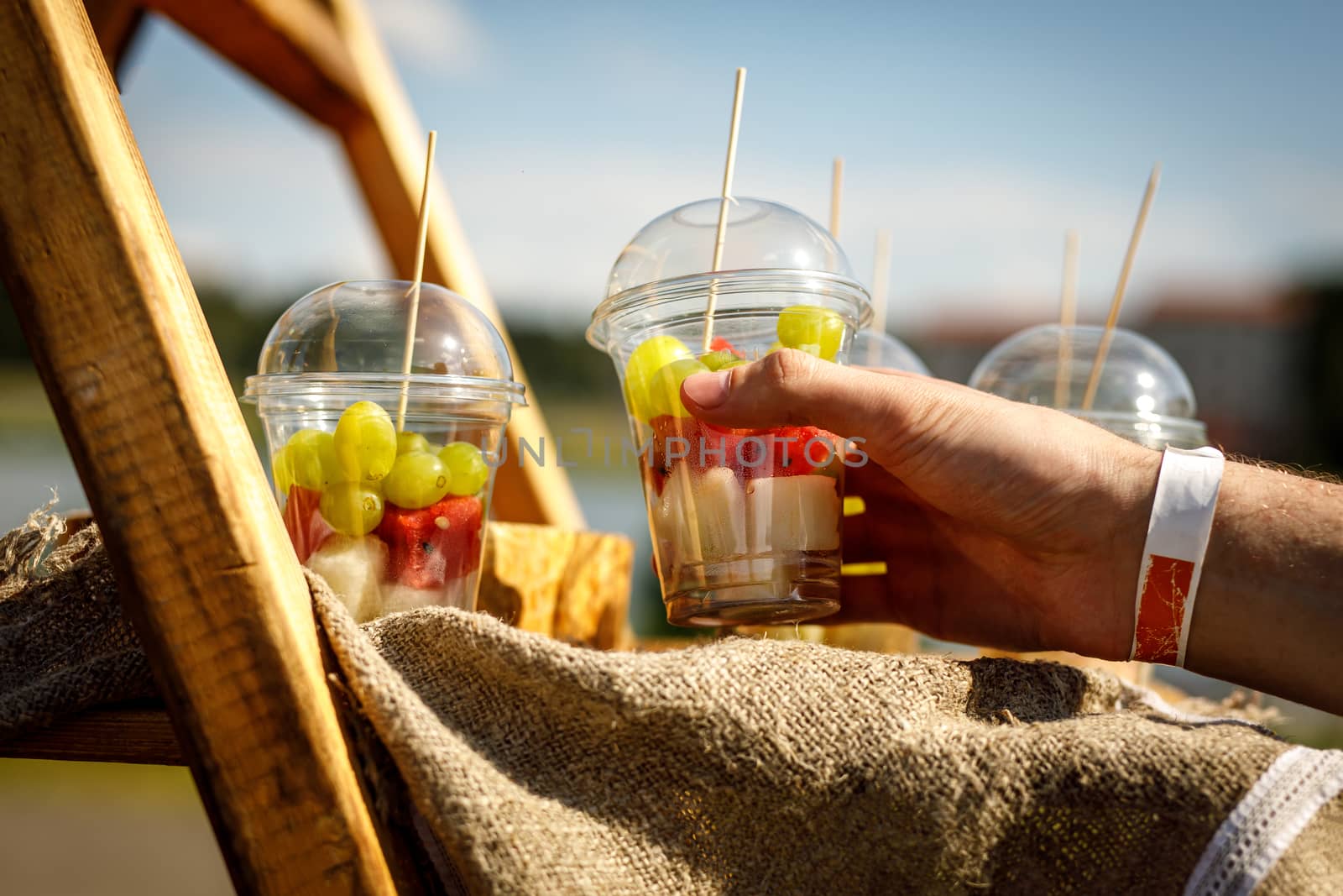 Hand takes fresh fruit pieces salad in plastic glass by 9parusnikov