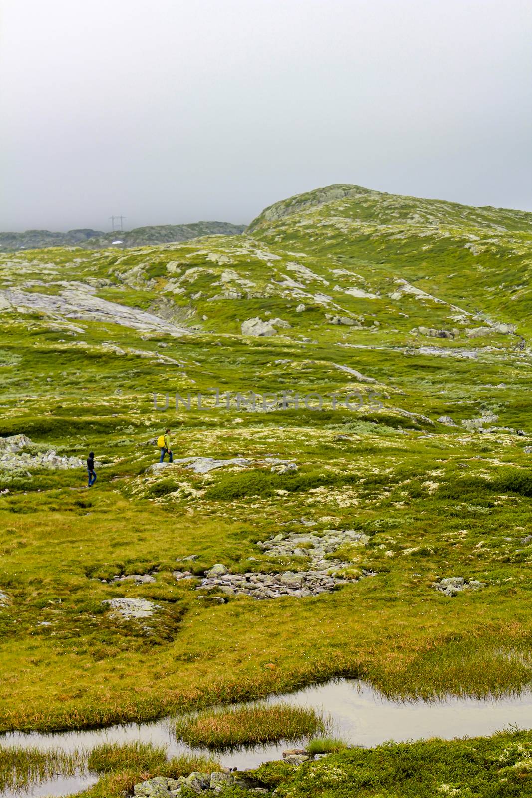 Hikers on the Hydnefossen waterfall and Hydna river on Veslehødn Veslehorn mountain in Hemsedal, Norway.