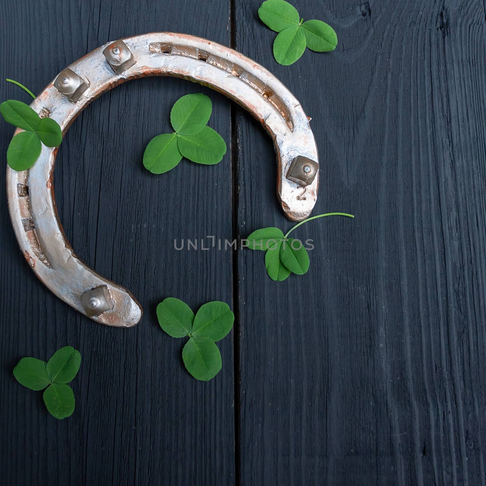 clover leaves and golden horseshoe on vintage wooden boards. Good luck symbol, St. Patrick's Day and New Year concept. by bonilook