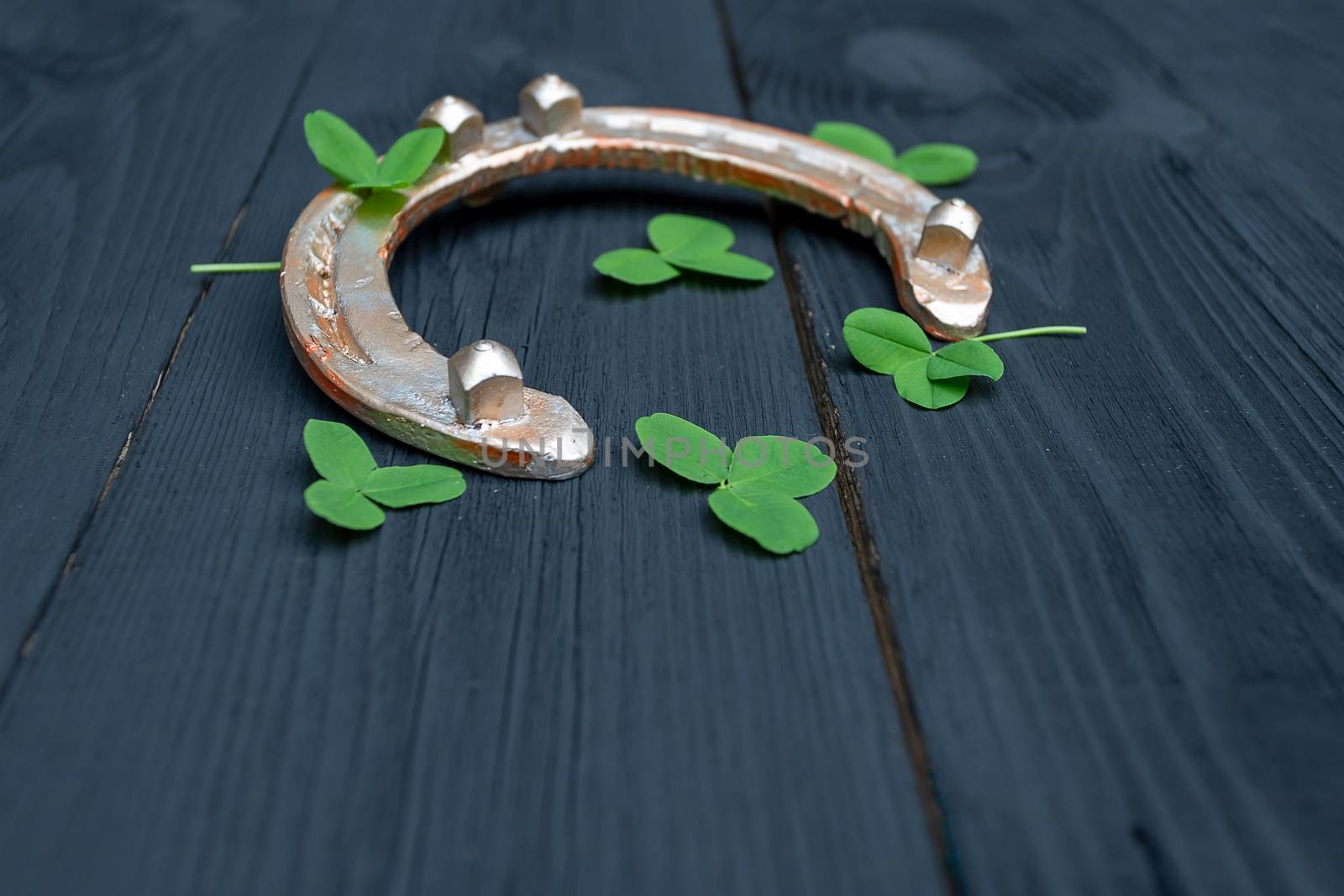clover leaves and golden horseshoe on vintage wooden boards. Good luck symbol, St. Patrick's Day and New Year concept. by bonilook