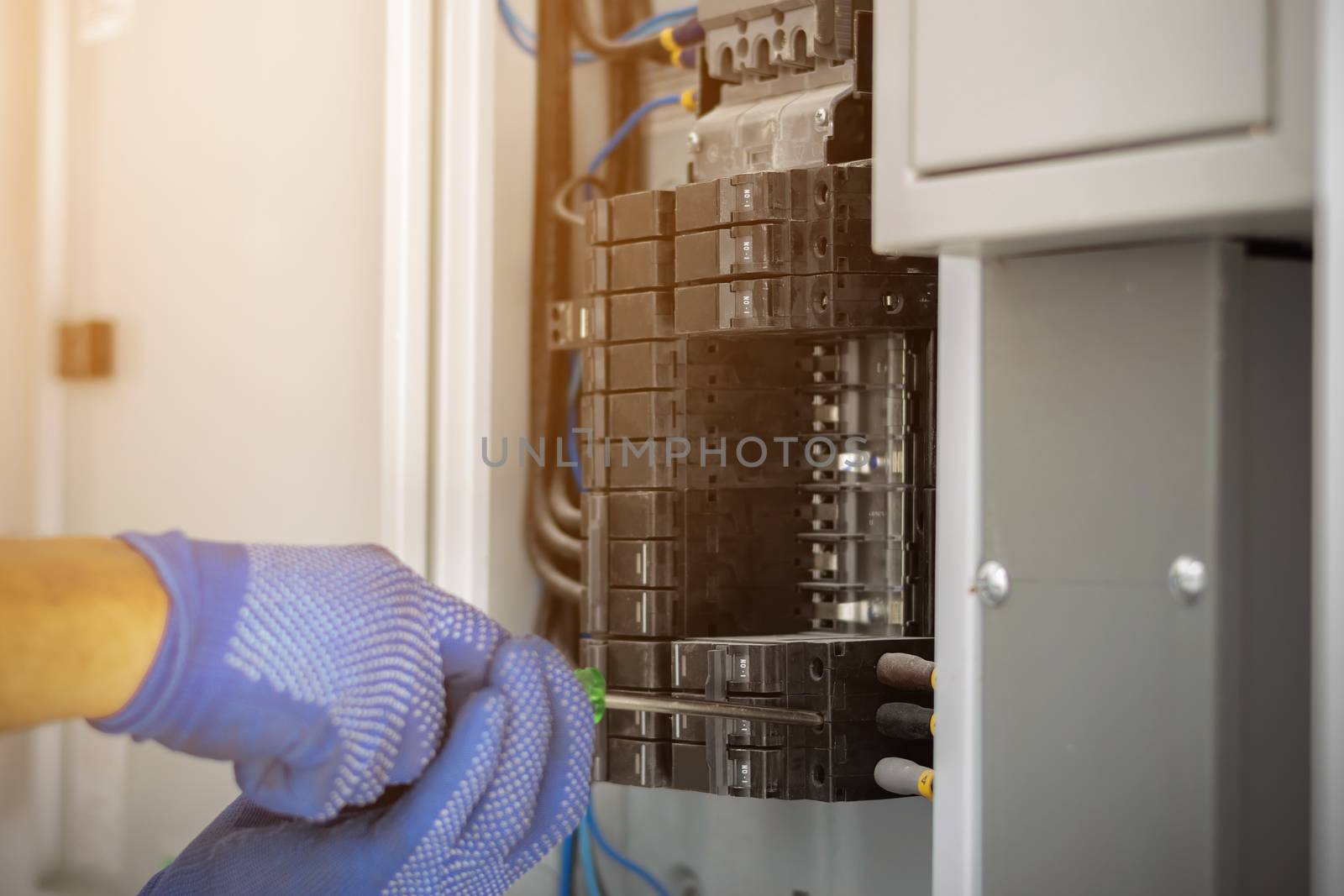 Electrician is using a screwdriver to install the breaker in the electrical control cabinet of the building.