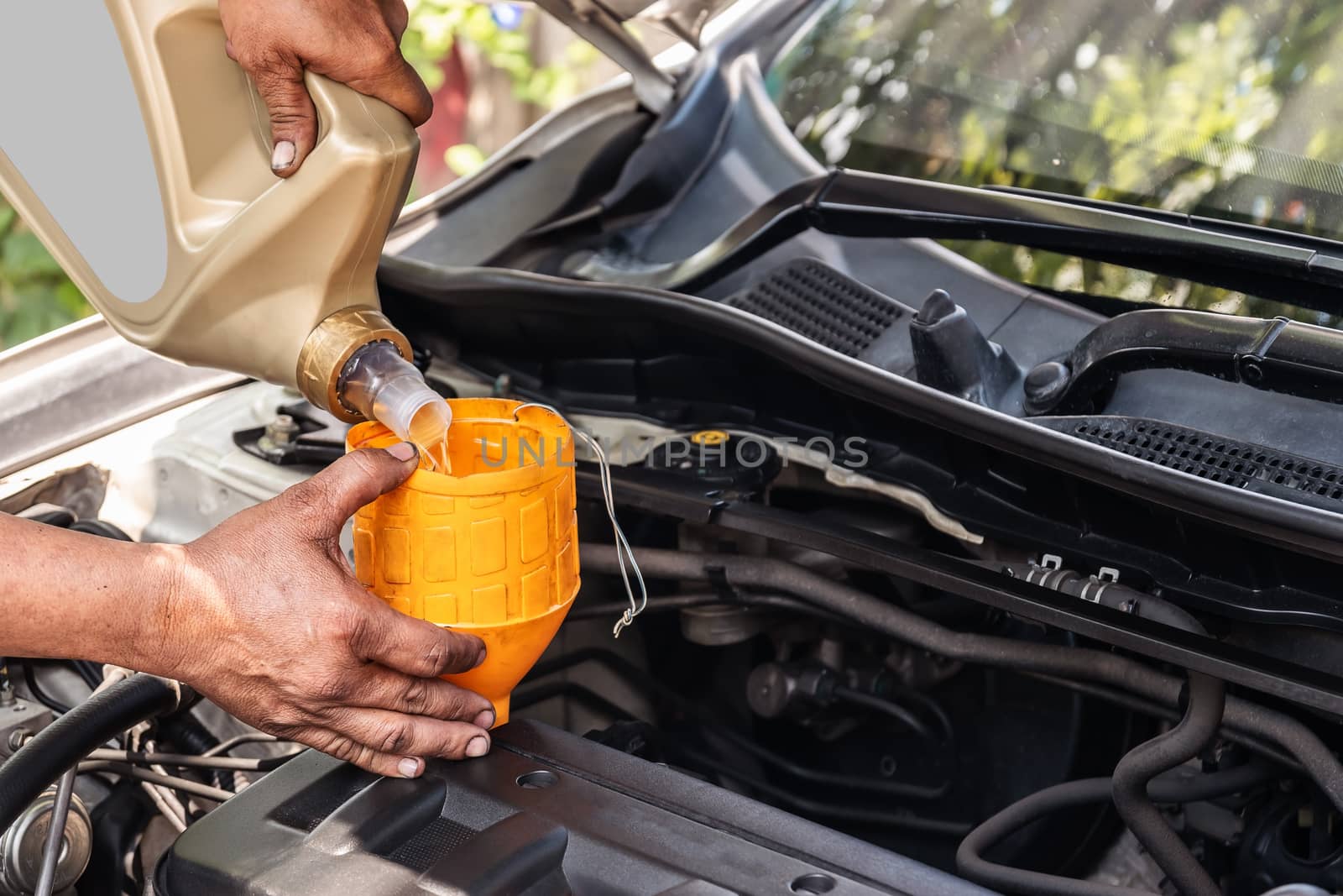 Car mechanic is adding oil to the engine, Automotive industry and garage concepts.