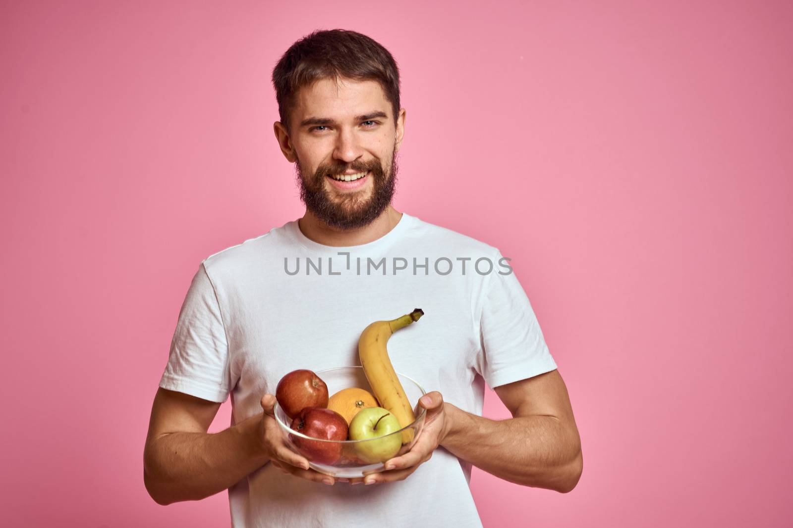 energetic man with fresh fruit in a cup on a pink background copy space by SHOTPRIME