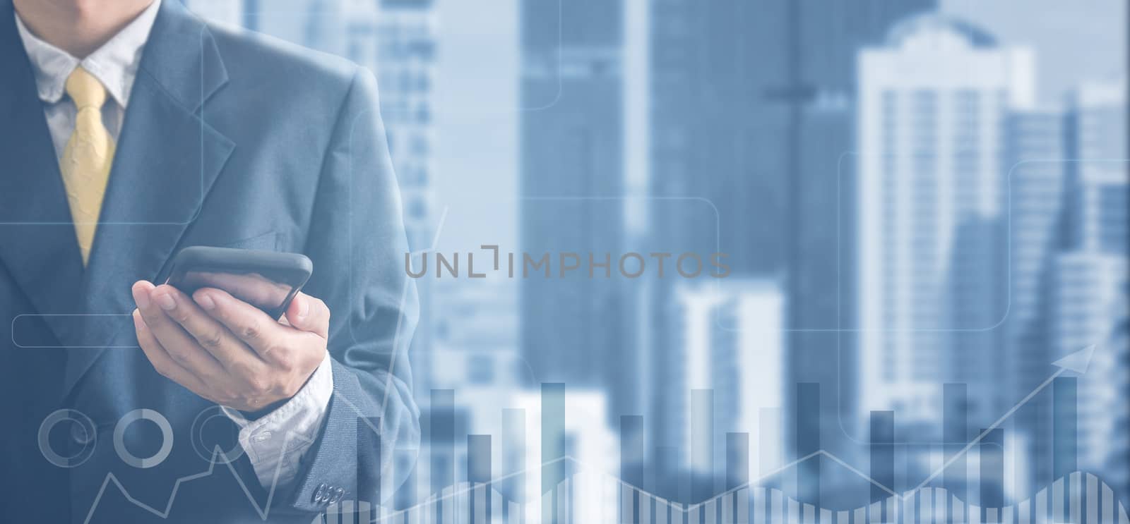 Double exposure hand of a business man in black suit is holding a mobile phone on a cityscape background. Analyze graphs and charts of business growth.Copy space 