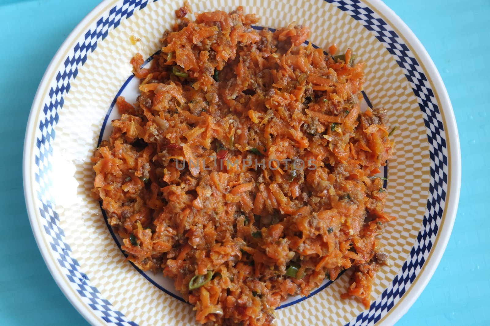 Top closeup view of a homemade dish made from carrot and vegetables served in a ceramic plate.