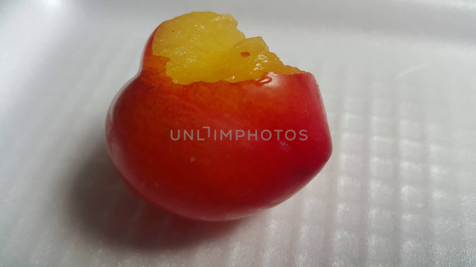 Closeup view of red plum on a white grey background. Freshly harvested plum making heart shape appearance in the view from angle.