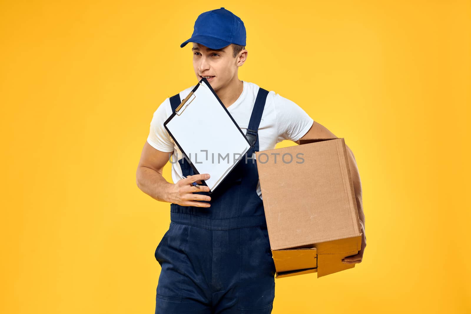 Working man in uniform with box hand delivery loading service yellow background. High quality photo